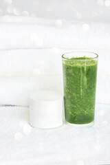 Green smoothie juice of vegetables and face cream in a white jar. The concept of cleansing the body of toxins. Organic energy eating. Athlete vitamic shake. Health lifestyle
