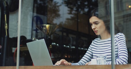 Caucasian attractive woman working at the computer while sitting in the cafe and drinking coffee.