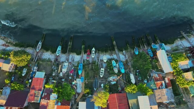 Aerial footage of docked boats, tilting up the camera slowly revealing shadows from houses in the sea, cinematic