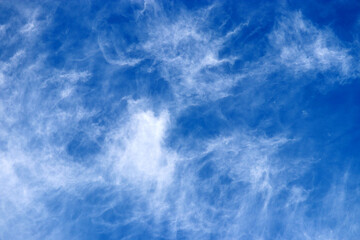 Blue sky covered with white cirrus clouds. Summer cloudscape, beautiful weather background