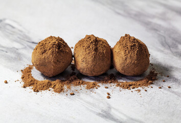 Homemade energy balls with dried apricots, raisins, dates, prunes, walnuts and cacao. Healthy sweet food. Energy balls on a marble grey background. Close up. Side view. Copy space
