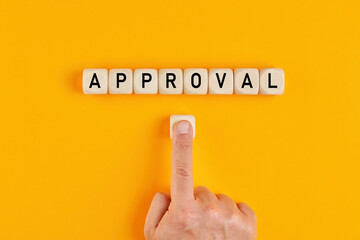 The word approval written on wood blocks with a male hand pushing the button. Concept of approving...