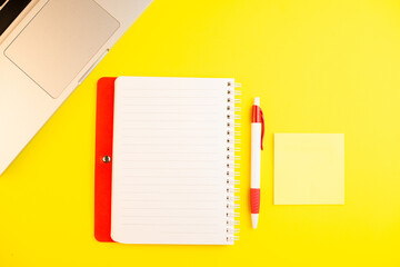 Pen, laptop, notepad planner and note stick on yellow background. Flat lay. Copy space. Workplace in the office.