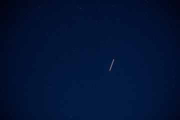 Obraz na płótnie Canvas a satellite flies high up in the sky in the dark night