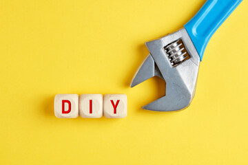 The word DIY do it yourself written on wood cubes with a wrench