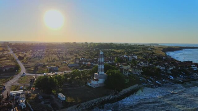 Cinematic aerial footage of a drone flying around an old lighthouse while the sun is setting