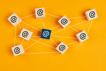 Email at symbol on wooden cubes linked each other with lines. Email traffic or chain mail concept
