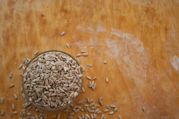 Sunflower seeds in a bowl in the left bottom corner. Wooden bacground
