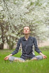 Yoga woman in spring park, sitting in a lotus, breathing