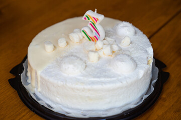 white birthday cake with candle number three. 