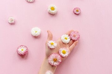 Summer flowers in hand on pink background. Health and medicine concept, spa, cosmetology. Copy space.