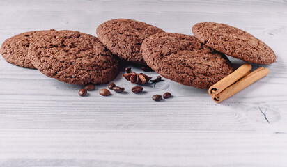 Freshly baked chocolate cookies decorated with coffee beans, star anise, cinnamon sticks, cloves on a white wooden table background with copy space. Image design for cafe menu layout.