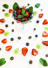 composition with berries and berry mixture in a crystal glass with strawberries, blueberries, blueberries and mint close-up