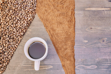Top view of a cup of coffee on the table with roasted and ground coffee beans on it