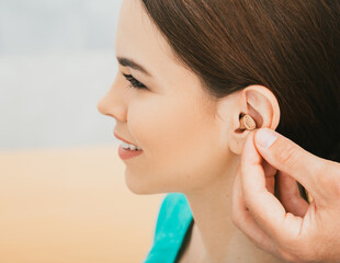 Young patient with Intra-ear hearing aid, close-up on female ear. The hearing solution, audiologist...