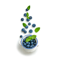 Blueberry flying in air, isolated on white. Fresh blueberry falling into bowl closeup, healthy diet concept. Ripe organic bilberry, mint leaf fly, creative minimal levitation concept.