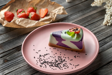 Blueberry cake, lemon, mint. Vegan, lactose free and sugar free. Laid on a pink plate, decorated with strawberries and sprinkled with black sesame seeds.