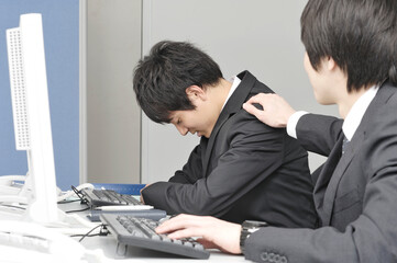 落ち込むビジネスマンを慰める同僚