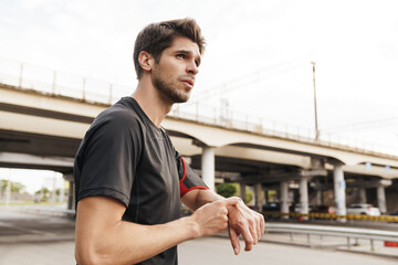 Image of athletic young sportsman using smartwatch while working out
