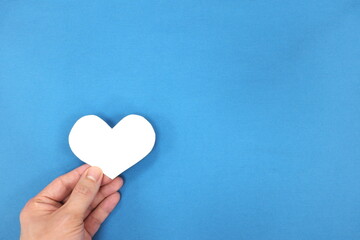 Male hands holding white heart shape. Charity and kindness concept. Top view with copy space.