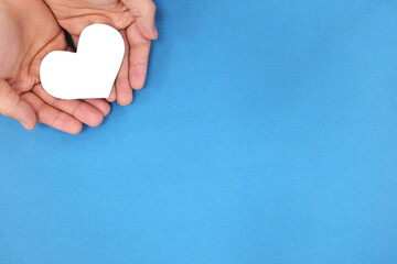 Male hands holding white heart shape. Charity and kindness concept. Top view with copy space.