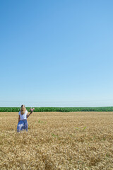 Naklejka na ściany i meble Woman walks in the wheat in a field