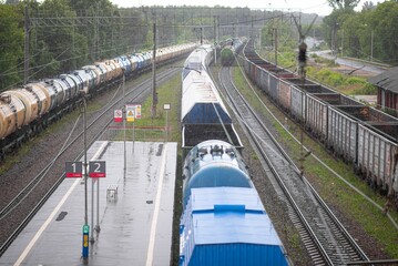 Railway station in rainy weather with standing freight cars and tanks.