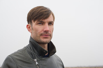Obraz premium man looks into the distance with his head turned to the side against the background of a light sky.