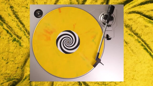 Yellow, green & red splatter 12&rdquo; vinyl record on a DJ turntable with yellow velvet background. Circular long player shot from above. Party, disco, rock, grunge, pop, house music. 60s, 70s, 80s, 90s 4K