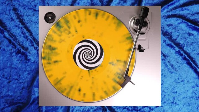 Yellow splatter 12&rdquo; vinyl record on a DJ turntable with blue velvet background. Circular long player shot from above. Party, disco, punky, grunge, RNB, R&B, Rythm & Blues, pop in 60s, 70s, 80s, 90s 4K