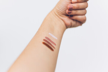 Female arm with different pastel colors on skin on white background. Modern makeup colors, home...