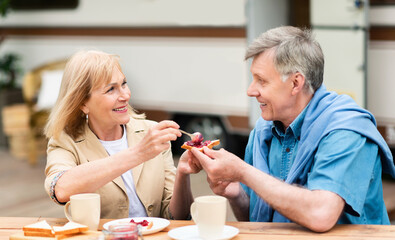 Elderly couple having breakfast together near motorhome outside