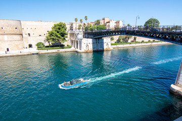 small boat that cross the swing bridge in front of the aragonian castle in taranto on blue sky...