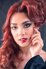 Fototapeta premium Caucasian Redhead with Half Face Painted with Natural Make-up and Half with Glam Make-up, Touching her Face, on Black Background