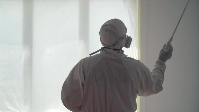 Industrial Painter In Full White Protective Suit Spray Painting Inside The Building - medium slowmo shot