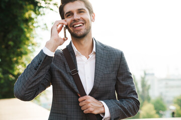 Cheery handsome business man talking by mobile phone