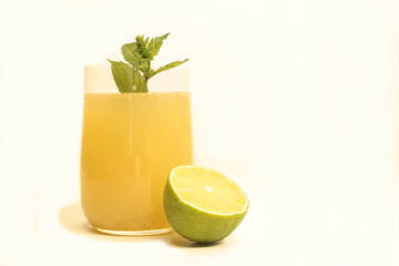 glass with lemonade, half a lime and a sprig of mint on a light background