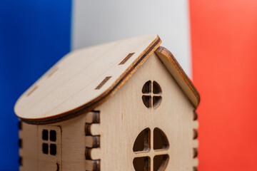 Obraz na płótnie Canvas Small wooden house, France flag on background. Real estate concept, soft focus