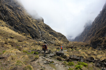 Trekkers traversing Annapurna Massif valley in Nepal Himalaya mountains