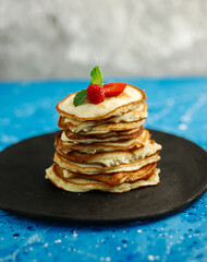 Pancakes with berries, dessert for breakfast on a blue background. Copy space for text