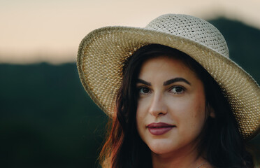 A portrait of a beautiful girl with a hat at sunset by the lake.