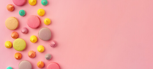 Pile of colorful macaroon cookies on pink background