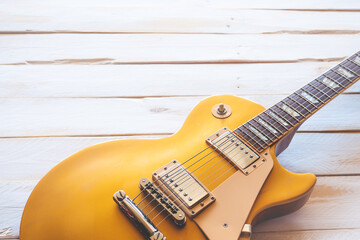 Beautiful classic golden electric guitar on a white wooden table, with copy space