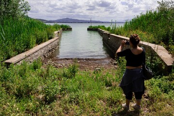 girl taking a picture of the landscape using a smartphone. View from the Polvese island in Lake...