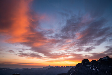 Colourful cloudy sunrise sky on mountain top in Swiss alps