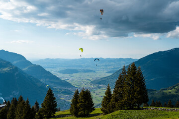 Paraglider rising over alpine valley on a cloudy summer afternoon in Switzerland