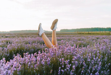 Feet up in white stylish sneakers in a beautiful lavender field.