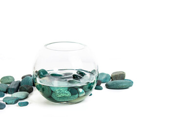 sea stones turquoise in water in a glass vase on a white background