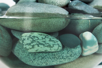 Turquoise sea pebbles in clear water close up