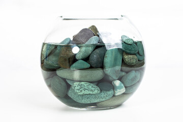 sea stones turquoise in a glass vase full of water on a white background